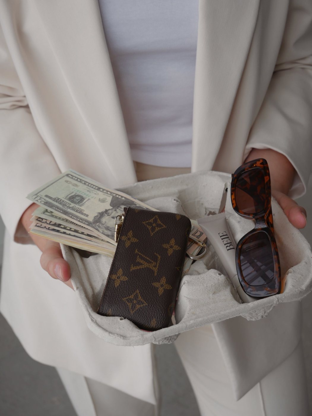 Hands holding cash, a wallet and sunglasses