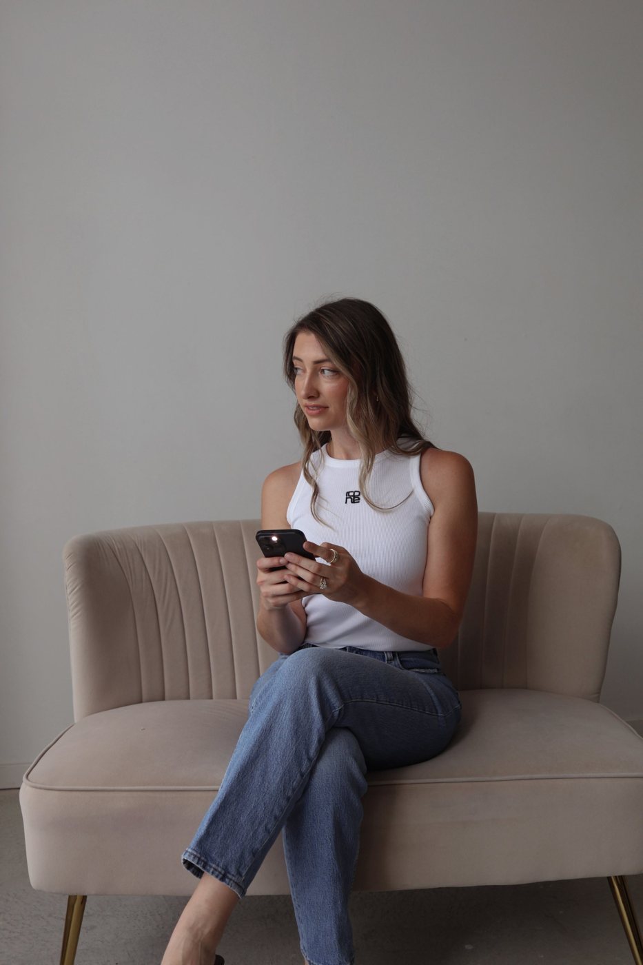 Hailey on a velvet loveseat, looking at her phone
